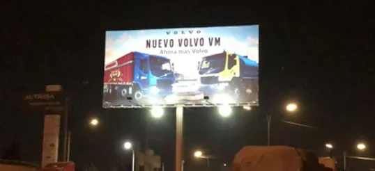 Billboard lit up at night beside an avenue