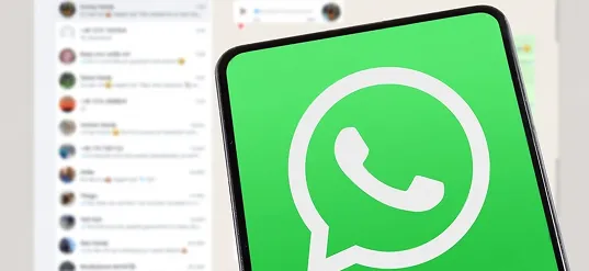 Phone showing the WhatsApp logo over a list of chats
