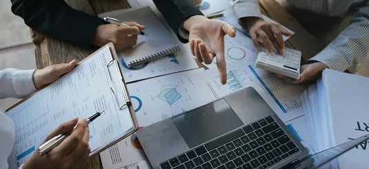 Team reviewing market charts and reports across a table